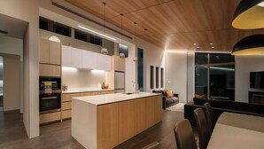 Una cocina moderna con una isla central, electrodomésticos integrados e iluminación colgante.