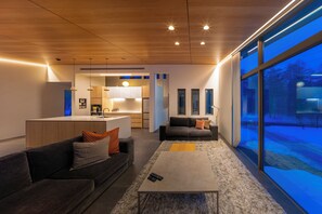 A modern living room with a sofa, coffee table, and a view of a snowy landscape through large windows.