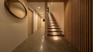 Un interior moderno con una escalera, pisos pulidos y un panel de madera.