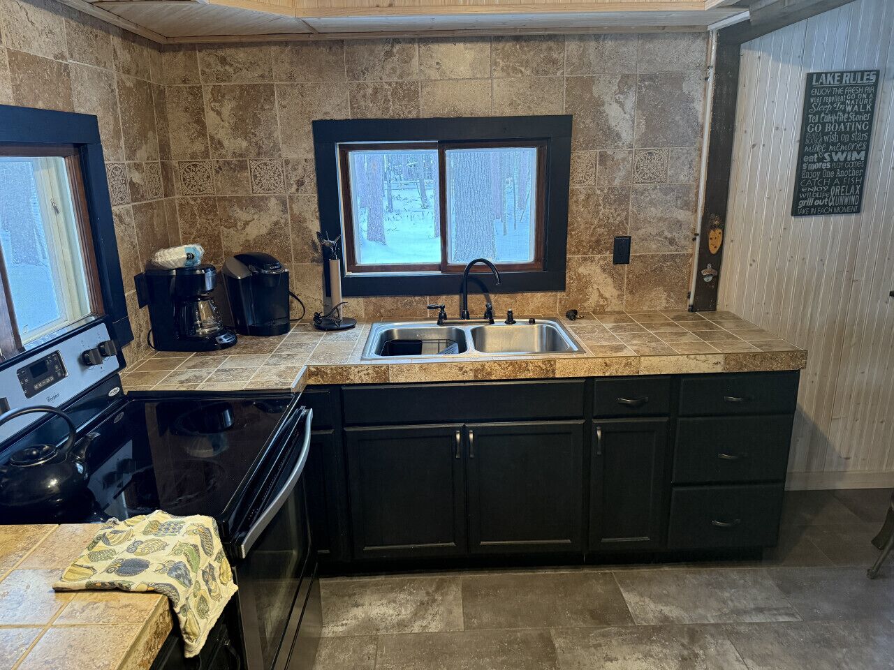 A kitchen with a large window, a stove, and a sink.