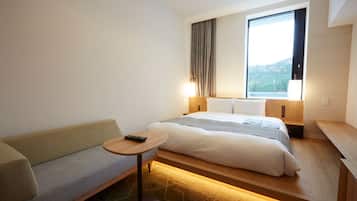 A hotel room with a bed, a sofa, a small table, and a window with a view of the outdoors.
