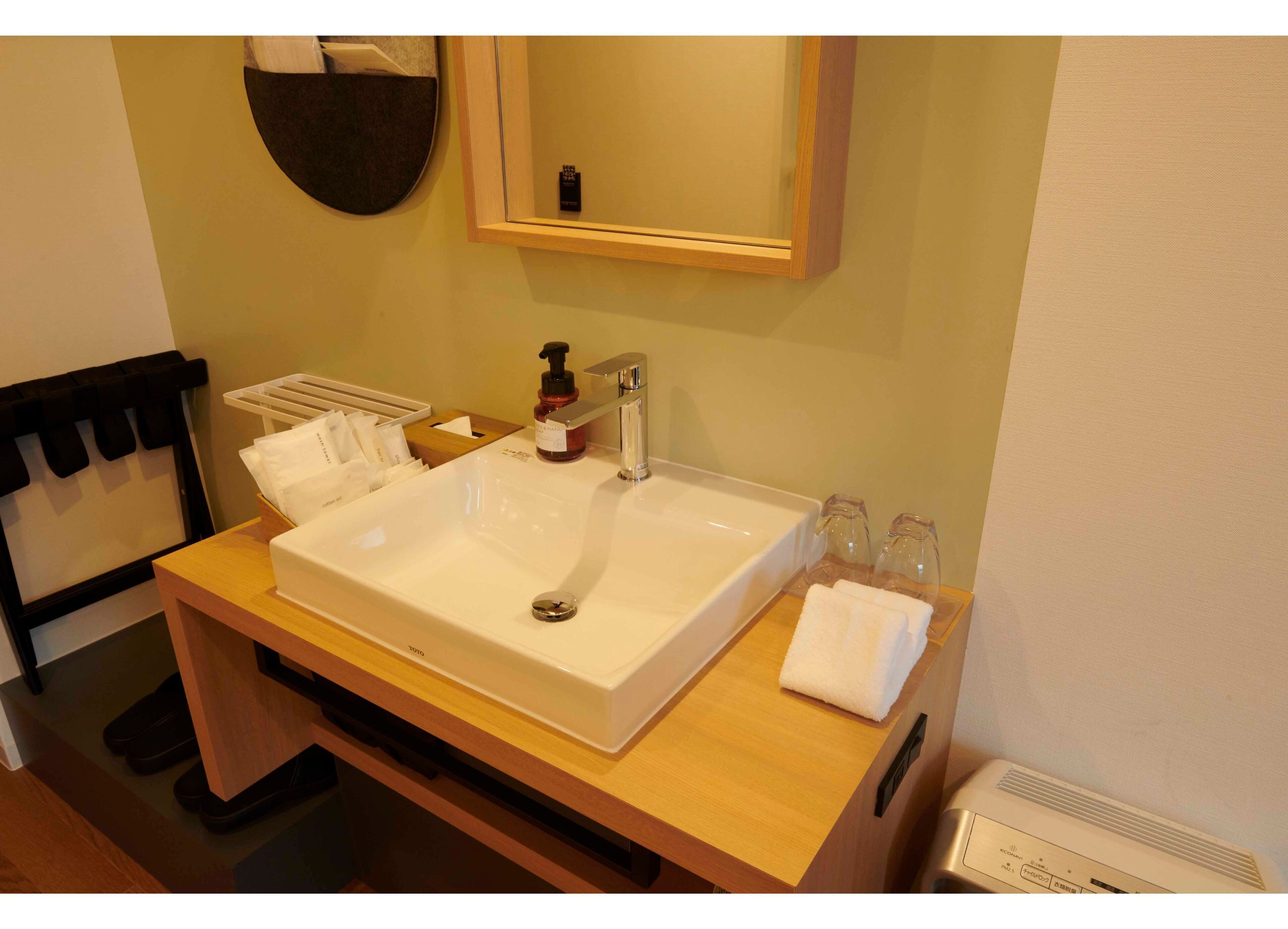 Un baño de hotel con un lavabo grande, un espejo, un perchero para toallas y una botella de jabón para manos.