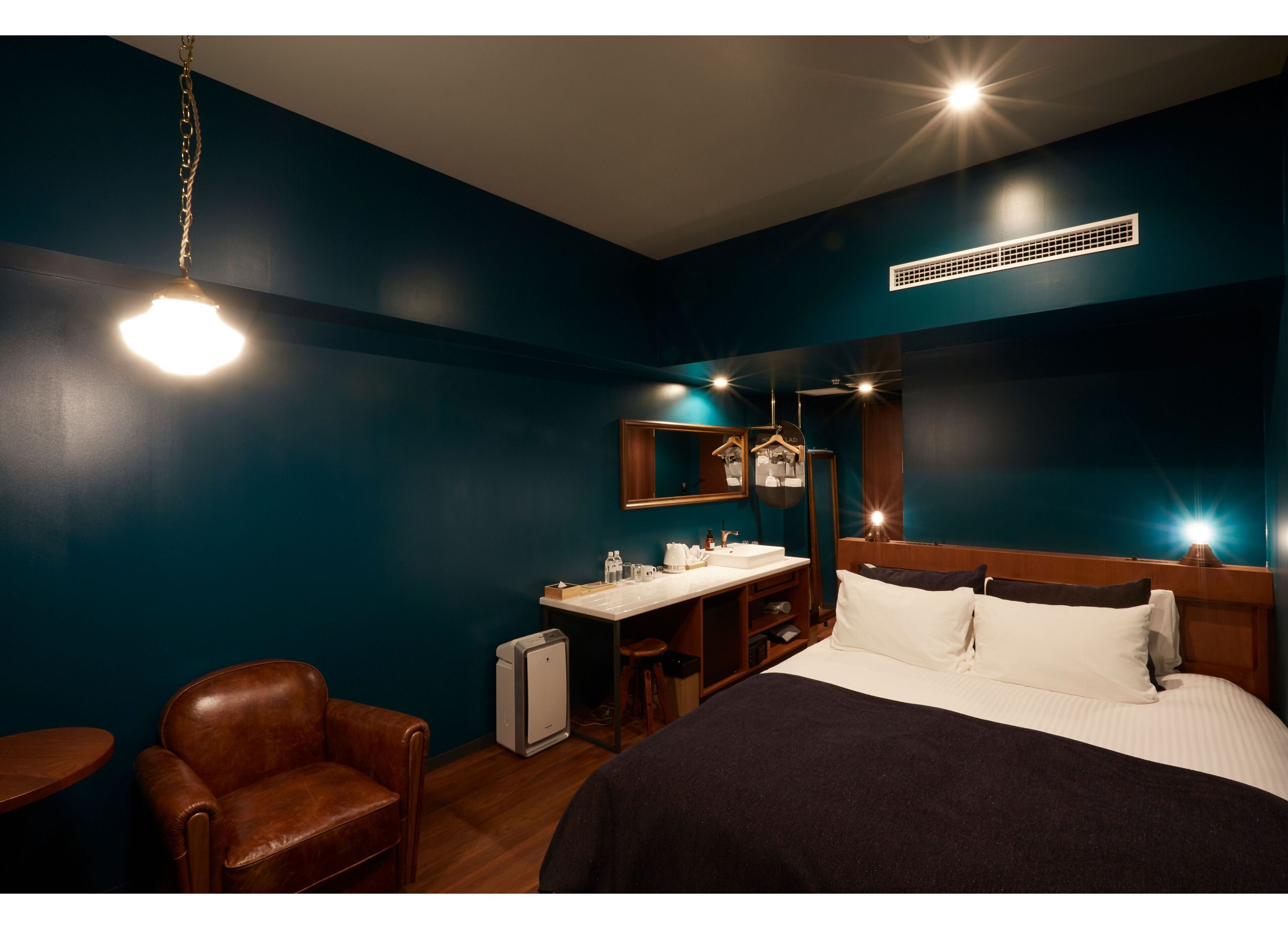 A hotel room with a bed, a desk, a chair, and a mirror.