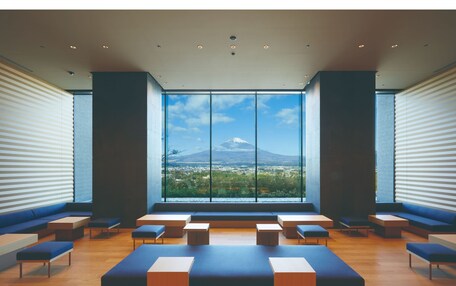 A modern interior with large windows, seating areas, and a view of a mountain.