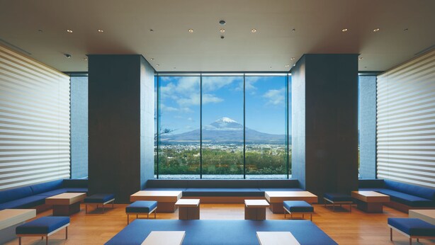Un interior moderno con ventanas amplias, zonas de estar y vistas a una montaña.