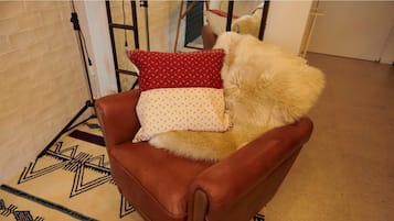A brown leather armchair with a patterned throw pillow and a fluffy white pillow.