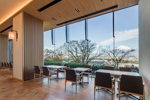 Un comedor moderno con ventanas amplias, suelo de madera y vistas a una montaña.