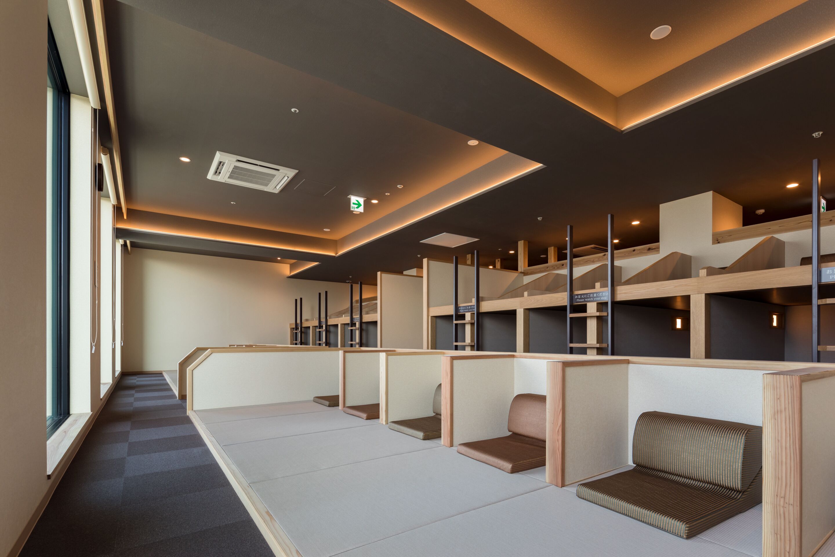 A modern hotel room with a long corridor, wooden partitions, and a staircase leading to an upper level.