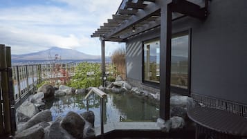 A modern outdoor pool area with a view of a mountain, surrounded by rocks and plants.