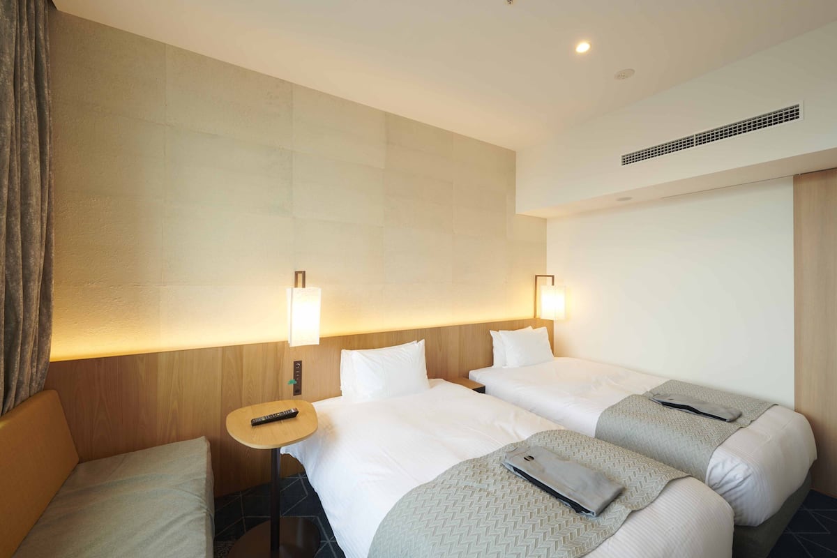 Ein Hotelzimmer mit zwei Betten, einem kleinen Tisch und einer Couch.