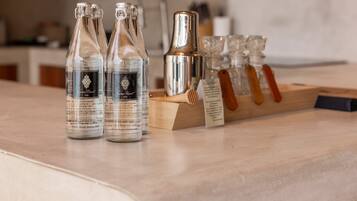 Drei Flaschen Kamma Resort Trinkwasser, ein silberner Cocktail-Shaker und ein Holztischchen mit Gläsern.