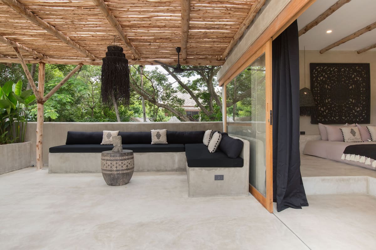 A covered outdoor seating area with a sofa and a decorative bowl.