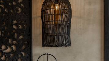 A modern room with a decorative wall panel, a hanging black pendant light, a wall-mounted lamp, and a woven basket on a marble console.