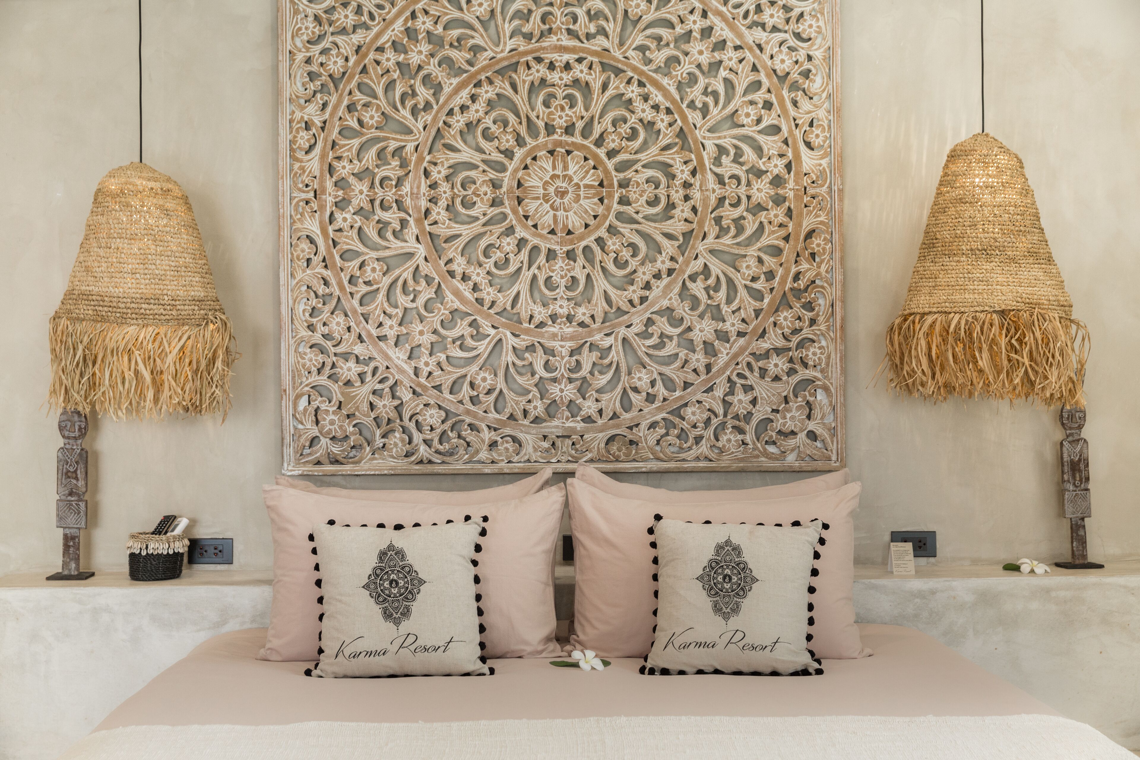 A bed with two pillows, a decorative wall panel, and two hanging lamps.