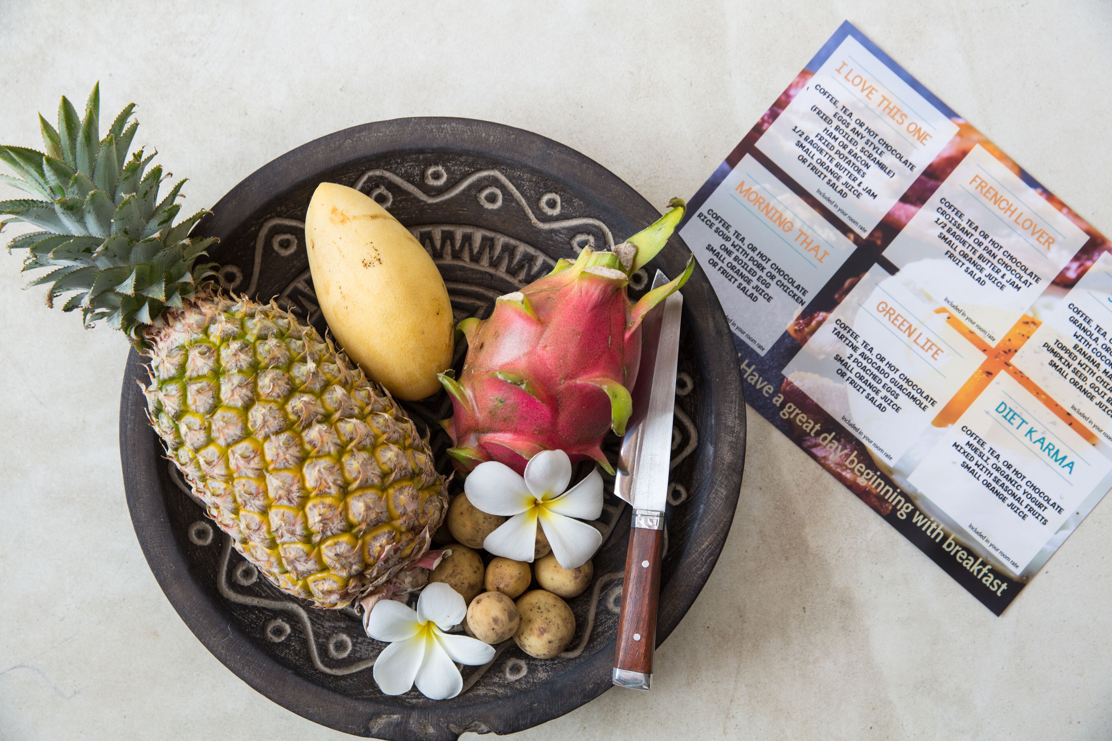 Un tazón con piña, pitahaya y flores de plumeria.
