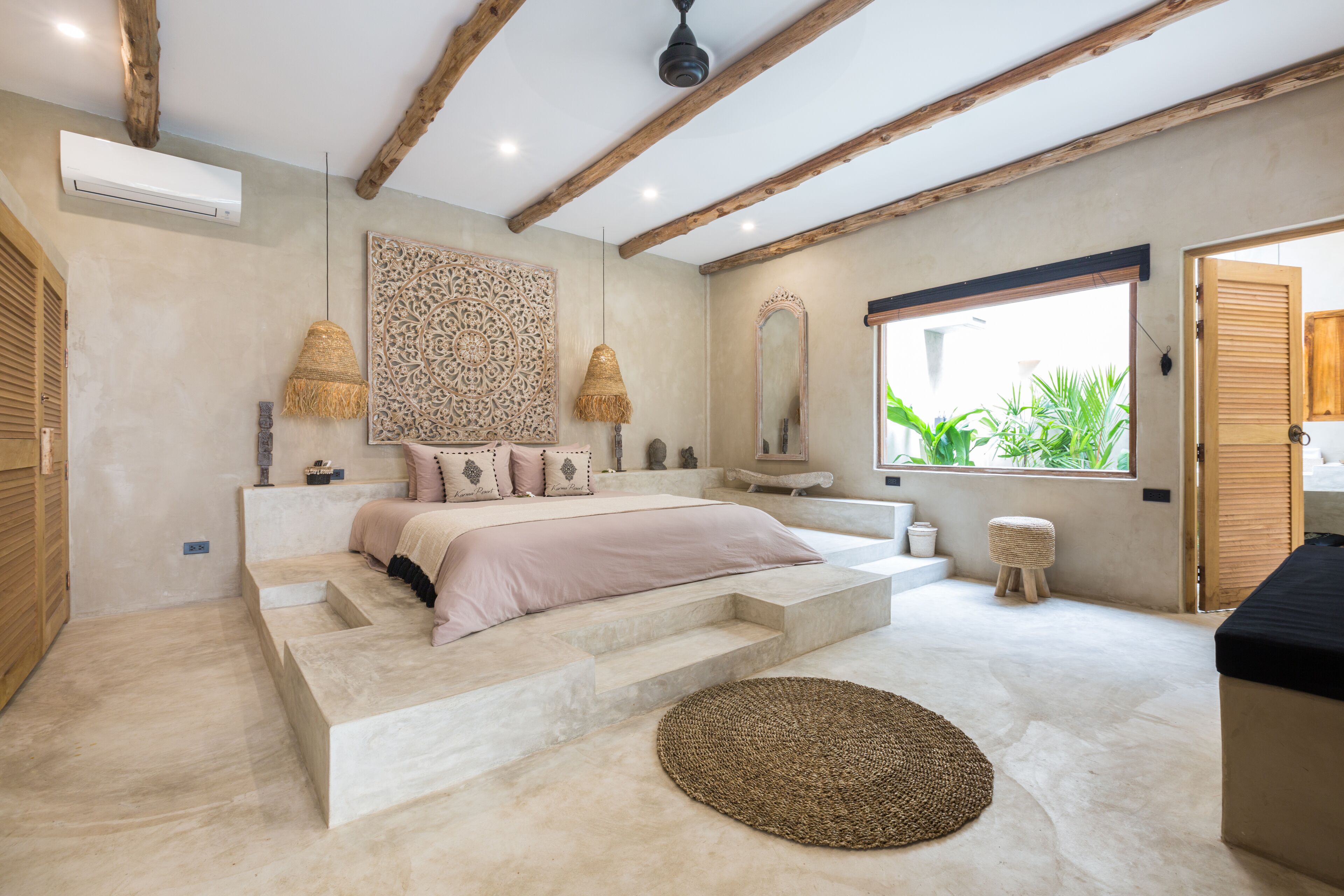 A bedroom with a bed, a large window, a mirror, and a staircase.