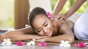 A person receiving a back massage on a wooden floor with flowers.
