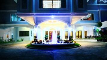 A large building with a central fountain, multiple windows, and a well-lit entrance.