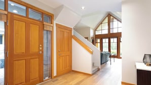 A spacious hallway with wooden doors, a staircase, and large windows. - Family-friendly townhouse w/ hot tub (Whistler)