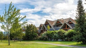 A lodge with multiple chalet-style buildings, a well-maintained lawn, and a clear sky. - Family-friendly townhouse w/ hot tub (Whistler)