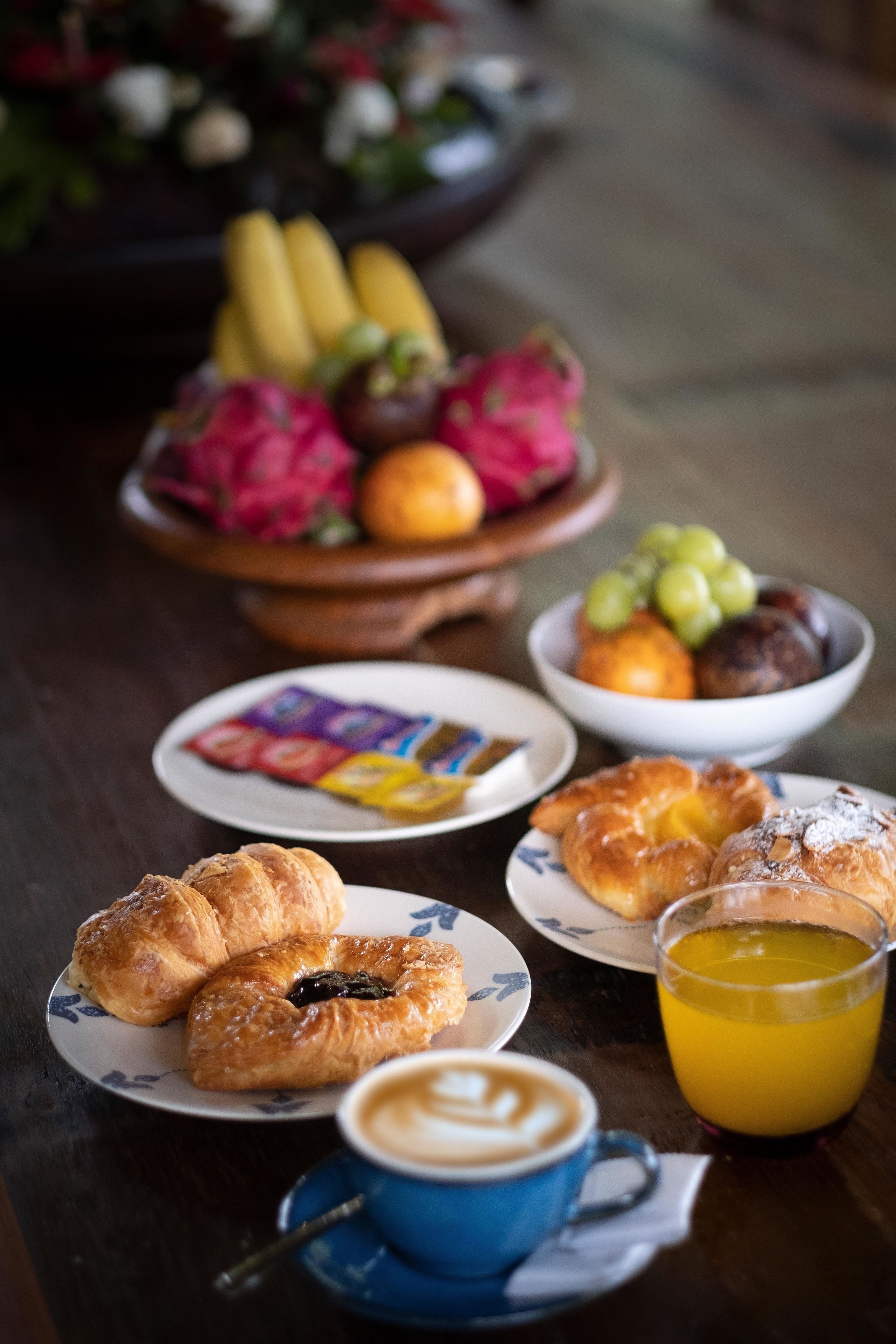 Una mesa con pasteles, fruta y una taza de café.