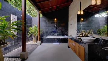 A modern bathroom with a large bathtub, two sinks, and a wooden vanity.