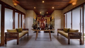 A hallway with a central statue, wooden benches, and a table with flowers. -  Ketewel Villa by Sanga Sanga Hospitality (Sukawati)