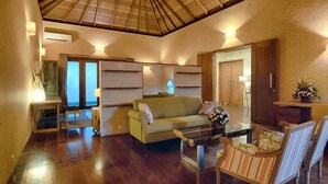 A spacious living area with a wooden ceiling, a sofa, a coffee table, and a dining table with chairs. -  Ketewel Villa by Sanga Sanga Hospitality (Sukawati)