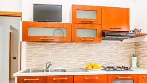 A kitchen with wooden cabinets, a stainless steel sink, and a gas stove. - Terra Mia (Agerola)