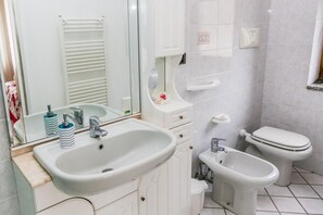 A bathroom with a sink, mirror, toilet, and bidet. - Terra Mia (Agerola)