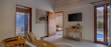 A spacious room with a wooden dining table, a TV mounted on the wall, and a sliding glass door leading to an outdoor area.