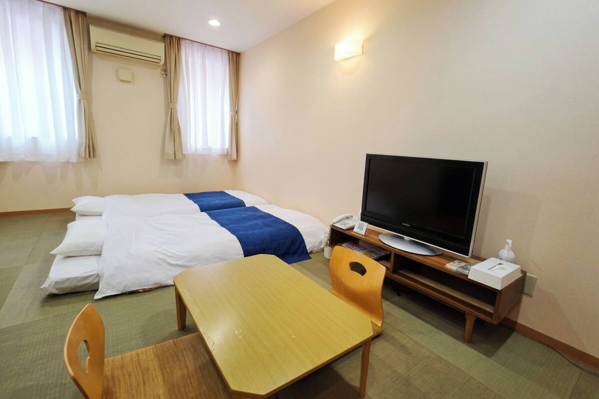 A hotel room with a bed, a television, a desk, and a chair.