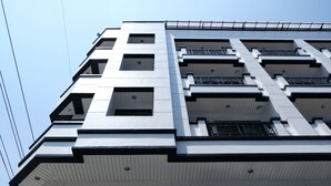 Un edificio moderno a più piani con una facciata simmetrica, caratterizzato da balconi e finestre su ogni piano.