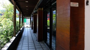 Un corridoio coperto con pavimento piastrellato, pareti in mattoni e porte in vetro che conducono a un ristorante.