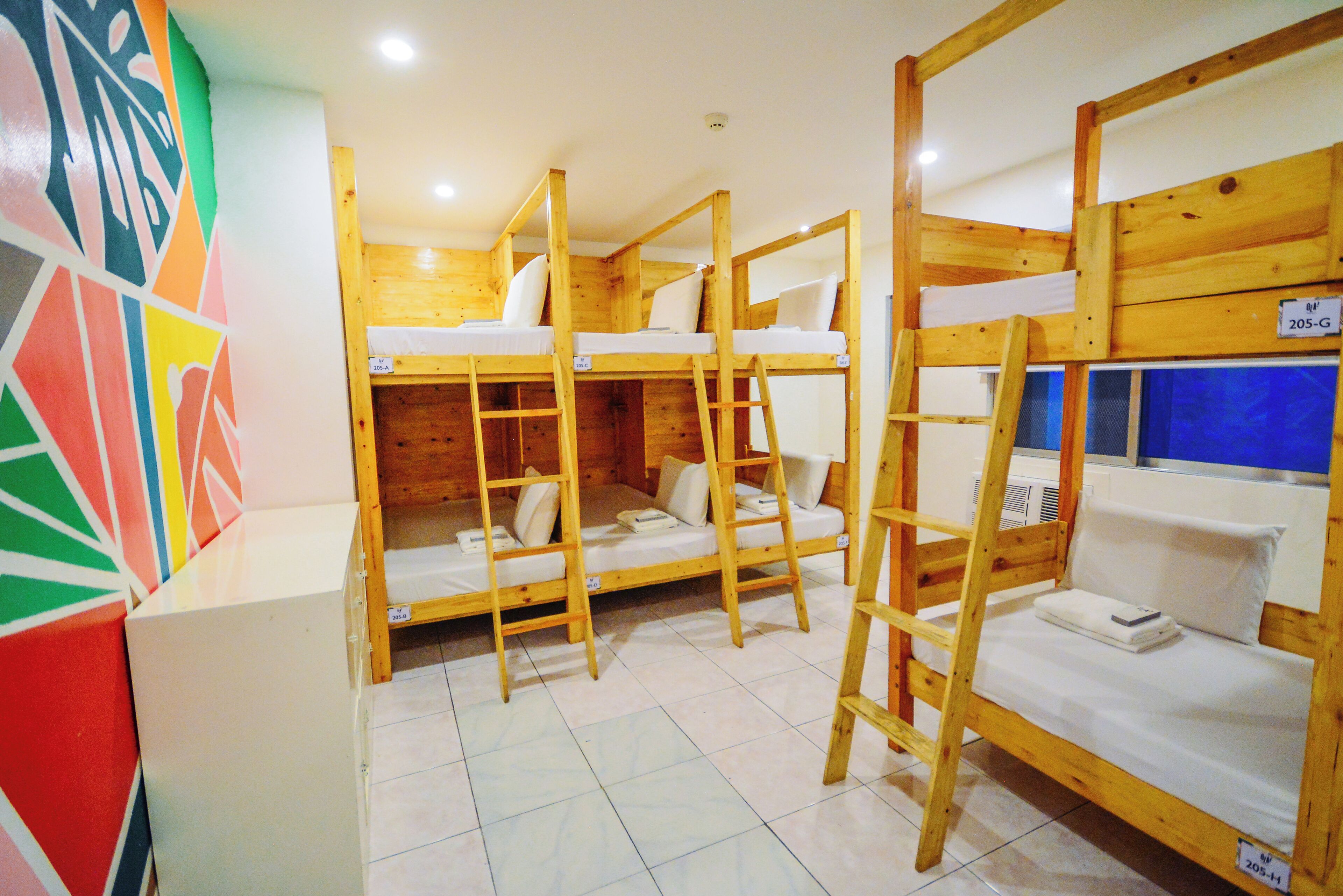 A room with bunk beds, a tiled floor, and a colorful wall.