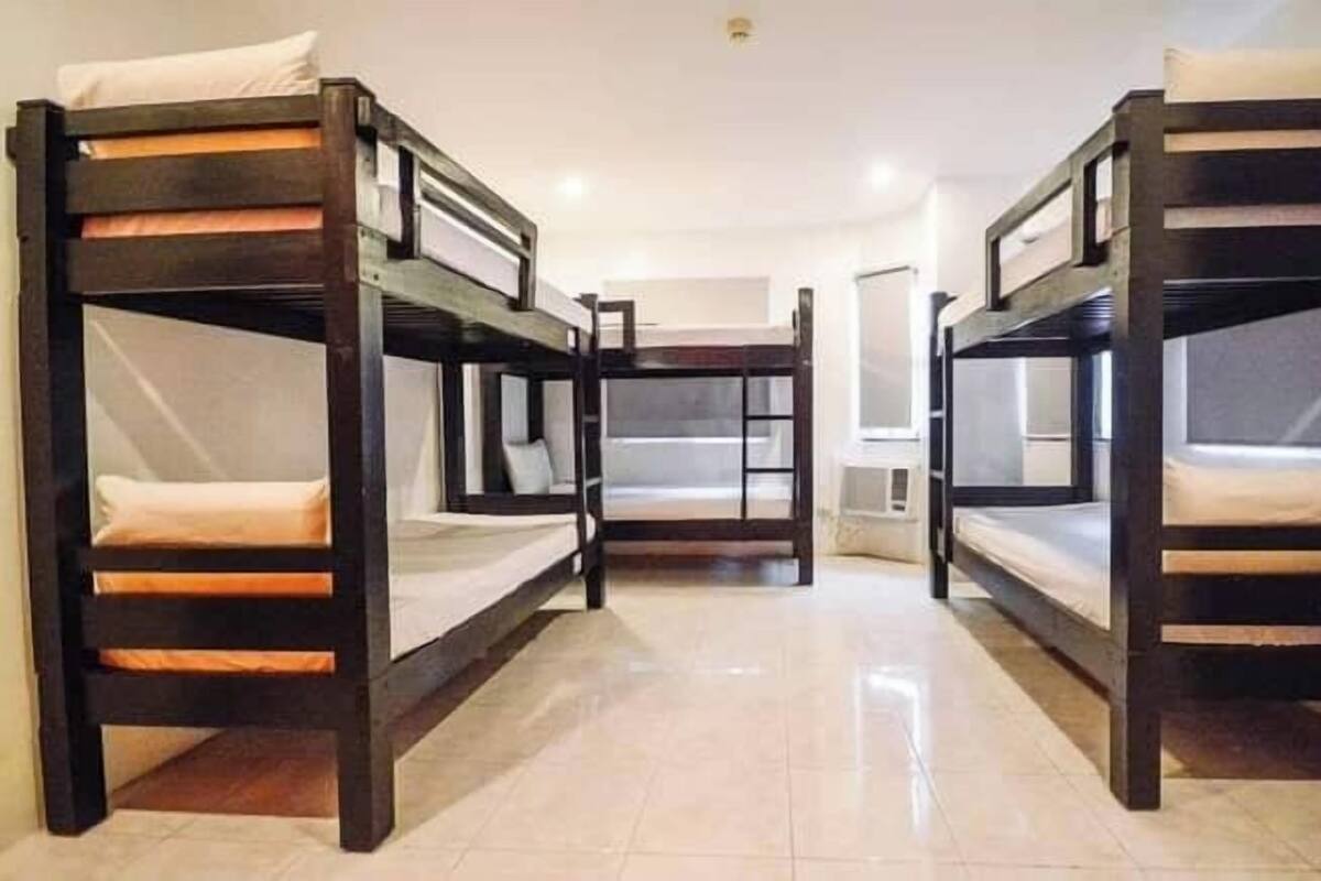 A room with three bunk beds, a white ceiling, and a tiled floor.