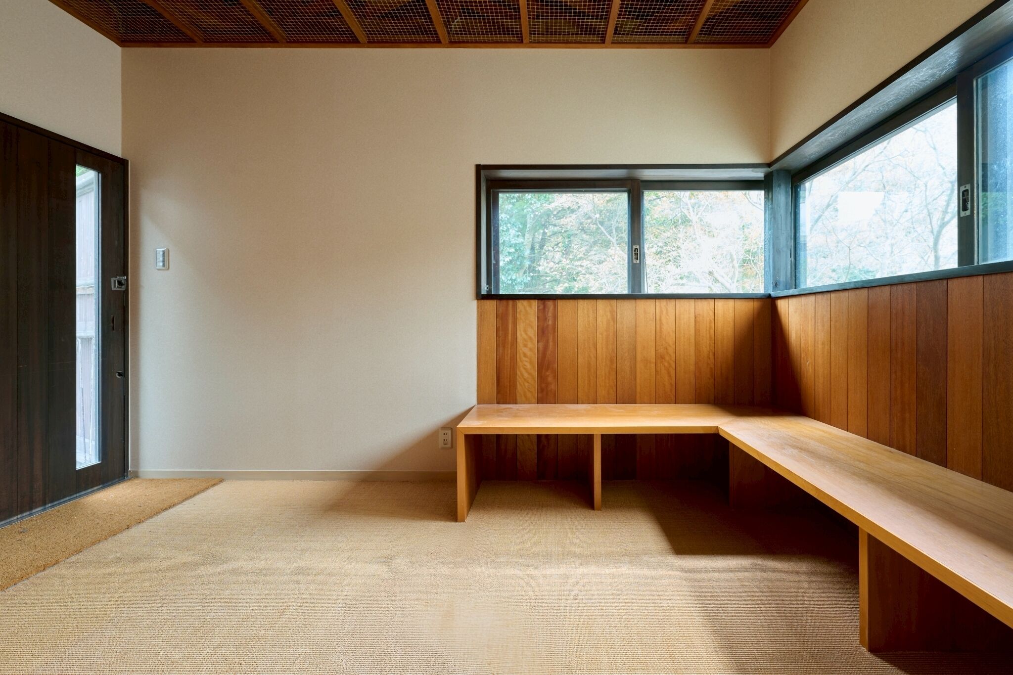 A room with a wooden bench, a large window, and a door.