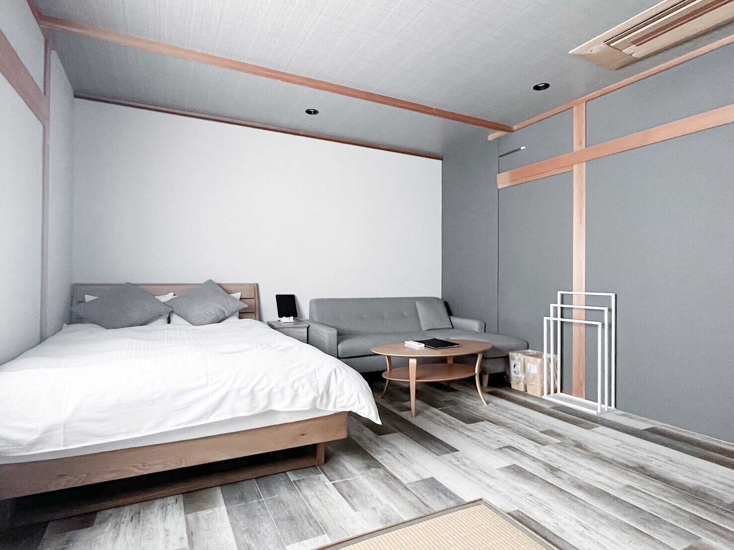 A modern bedroom with a bed, a sofa, a small table, and a window with a view.