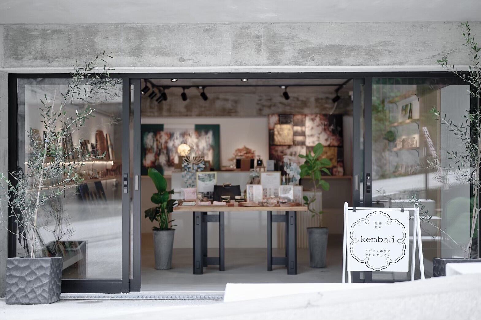 Un interior moderno con fachada de vidrio, una mesa de madera y plantas en macetas.