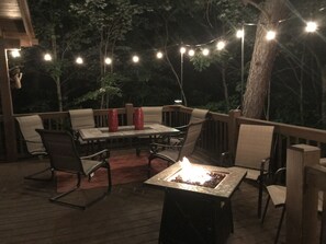 Eine Terrassengruppe mit Feuerstelle, Sitzgelegenheiten und Lichterketten.