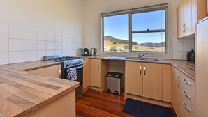 A compact kitchen with a gas stove, a sink, and a window overlooking a landscape. - Somerville Wine Cottage Hideaway 3Bedroom Cottage (Broke)