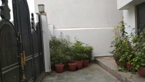 Un estrecho sendero de piedra conduce a una entrada con puerta, flanqueado por macetas con plantas.