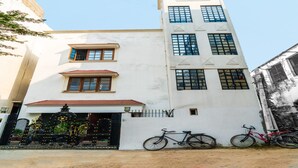 Un edificio de varios pisos con fachada blanca, techo rojo y una reja negra con detalles decorativos.