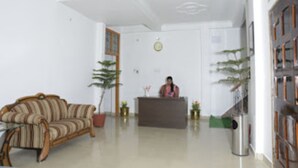 Una zona de recepción con mostrador, un sofá a rayas y plantas en macetas.