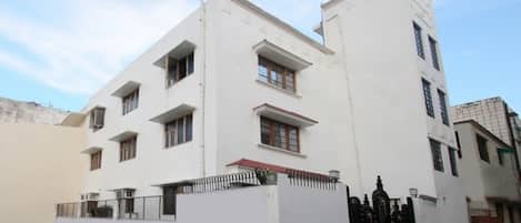 A modern white building with multiple windows and a gated entrance.