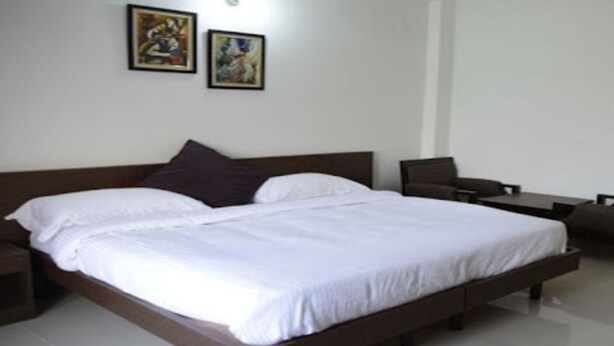 Una habitación de hotel moderna con una cama grande, una mesita de noche, una silla y dos cuadros en la pared.