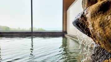 A stone water feature with water flowing over it, reflecting on the water surface.