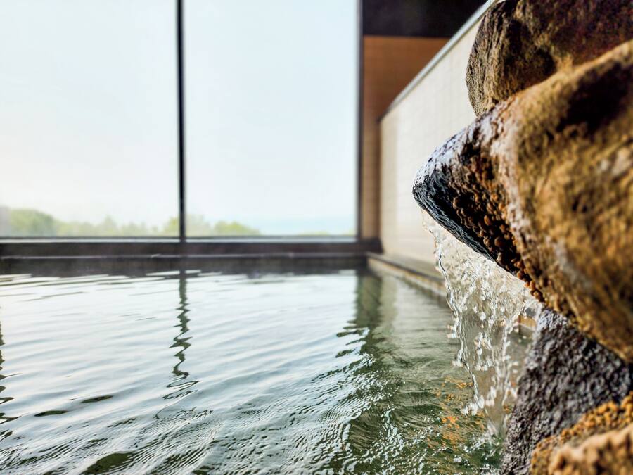 Una fuente de piedra con agua que fluye, reflejándose en la superficie.