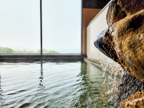 A stone water feature with water flowing over it, reflecting on the water surface. - Iwanai Kogen Hotel (Iwanai)