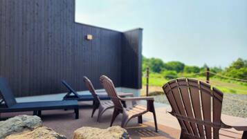 An outdoor seating area with lounge chairs and a table, surrounded by rocks.